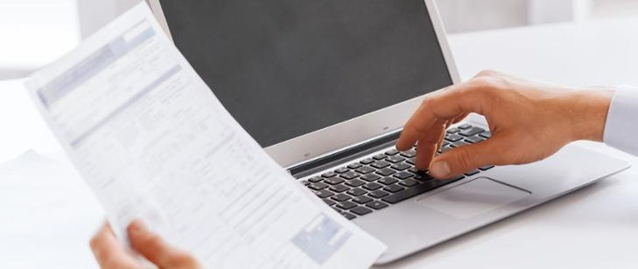 Na środku ekranu komputer. Z prawej strony dłoń wciskająca klawisze. Z prawej - dłoń trzymająca dokument.